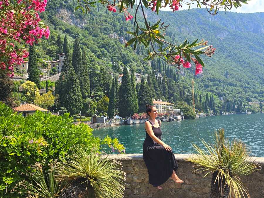 Milijana Gabrić sitting on a stone wall overlooking Lake Como at the botanical gardens of Villa Cipressi in Varenna, Italy