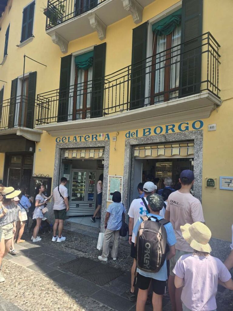 a crowd of people waiting outside the Gelateria del Borgo storefront in Bellagio