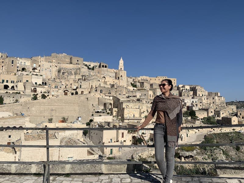 I Drove All Over Puglia, Italy — Here Are 6 Road Trip Itineraries That Actually Work Milijana Gabrić standing in front of the historic Sassi di Matera cave dwellings in Basilicata, Italy.