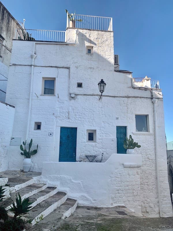 I Drove All Over Puglia, Italy — Here Are 6 Road Trip Itineraries That Actually Work Traditional whitewashed stone house with bright blue doors in the historic old town of Ostuni, Puglia, Italy.