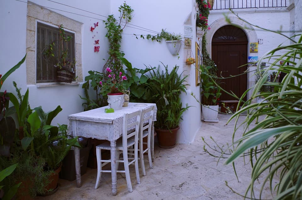I Drove All Over Puglia, Italy — Here Are 6 Road Trip Itineraries That Actually Work Rustic white wooden table and chairs in a whitewashed courtyard in Locorotondo, Puglia