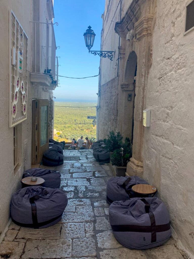 Outdoor cafe seating with beanbags outside Bar Perso in a narrow alley of Ostuni historic center, Puglia, Italy