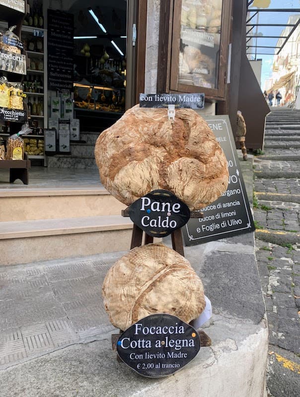 Food in Puglia: 23 Foods I Tried and Loved, From Cime di Rapa to Caffè Leccese Traditional Pane di Monte Sant'Angelo loaves and wood-fired sourdough focaccia displayed outside a bakery in Monte Sant'Angelo, Puglia, Italy.