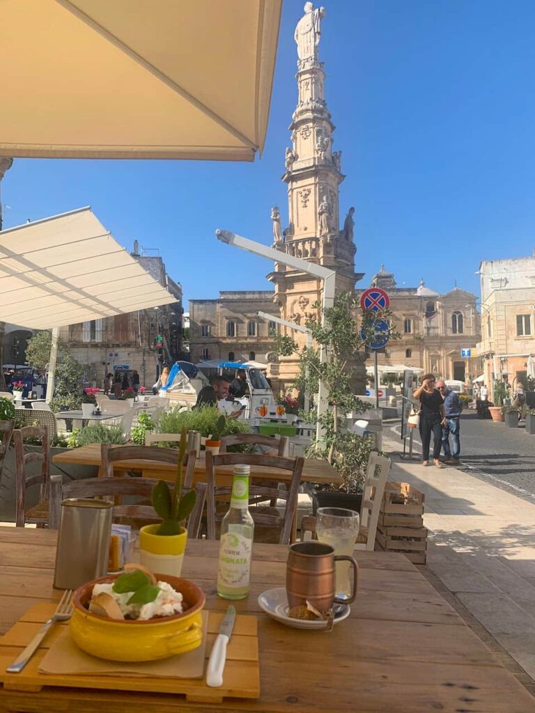 Outdoor café in Piazza della Libertà with the Guglia di Sant'Oronzo in Ostuni, Italy.