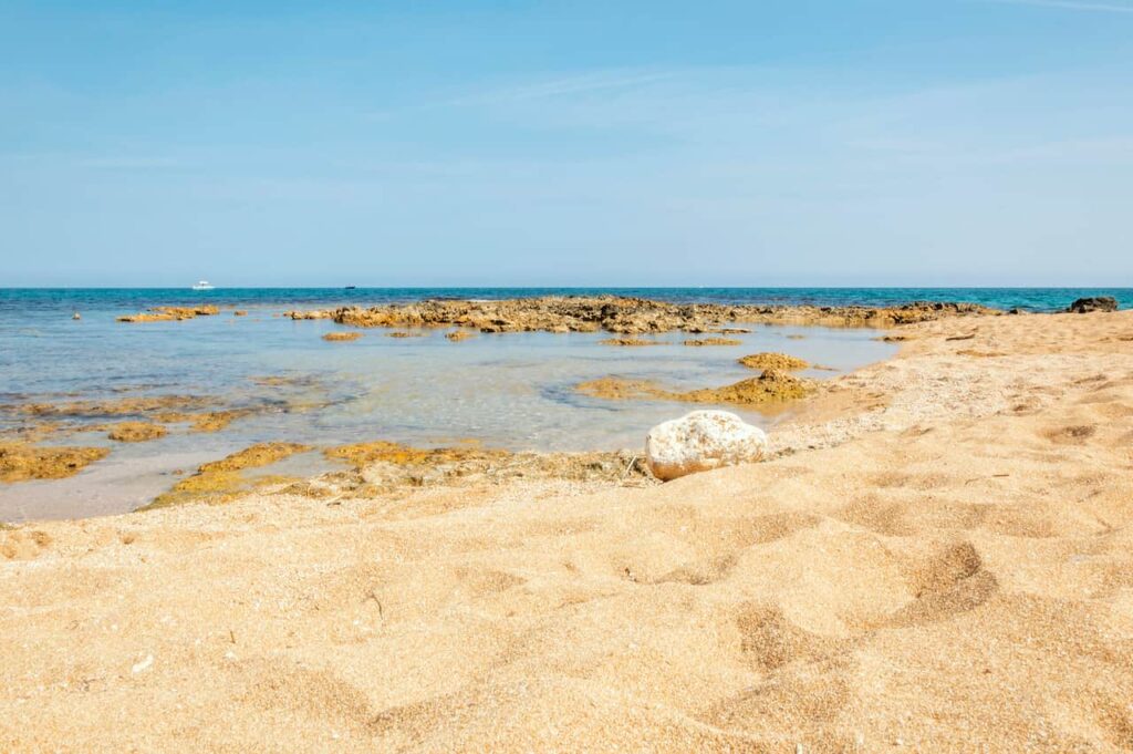 Sandy shore and shallow rocky coastline of Spiaggia di Creta Rossa near Ostuni, Puglia, Italy
