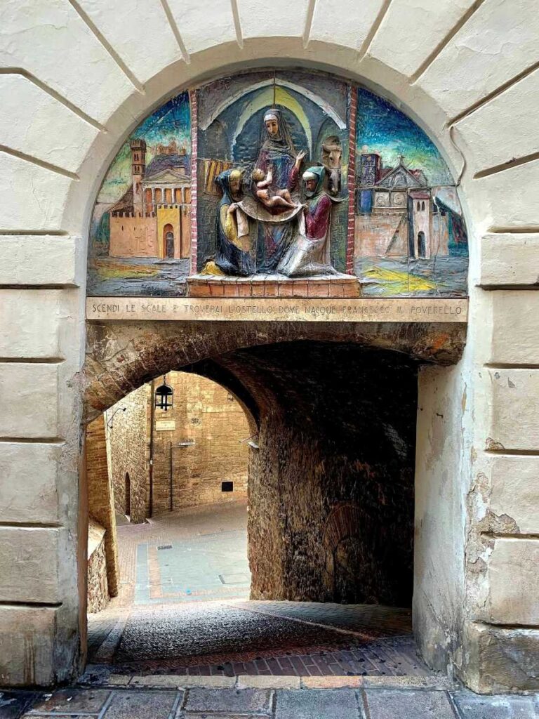 Arched passageway in Assisi, Italy, with a ceramic lunette of the Nativity of St Francis marking his birthplace