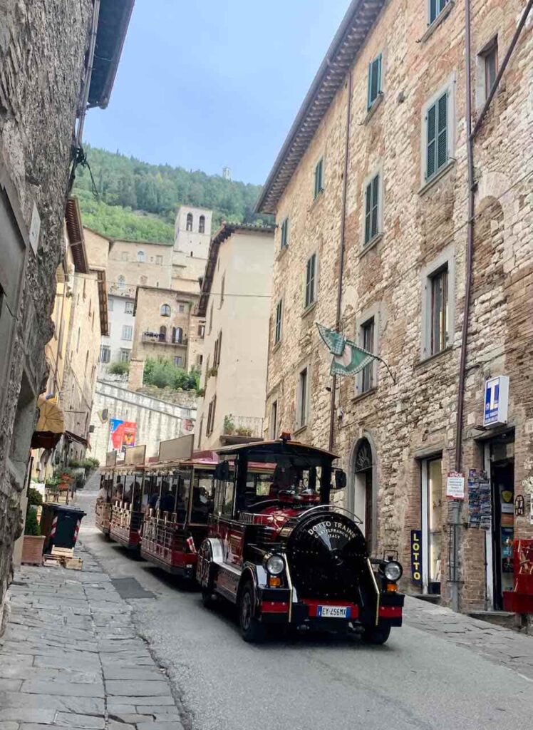 Gubbio Express panoramic tourist train on a street in the historic medieval town of Gubbio, Umbria, Italy