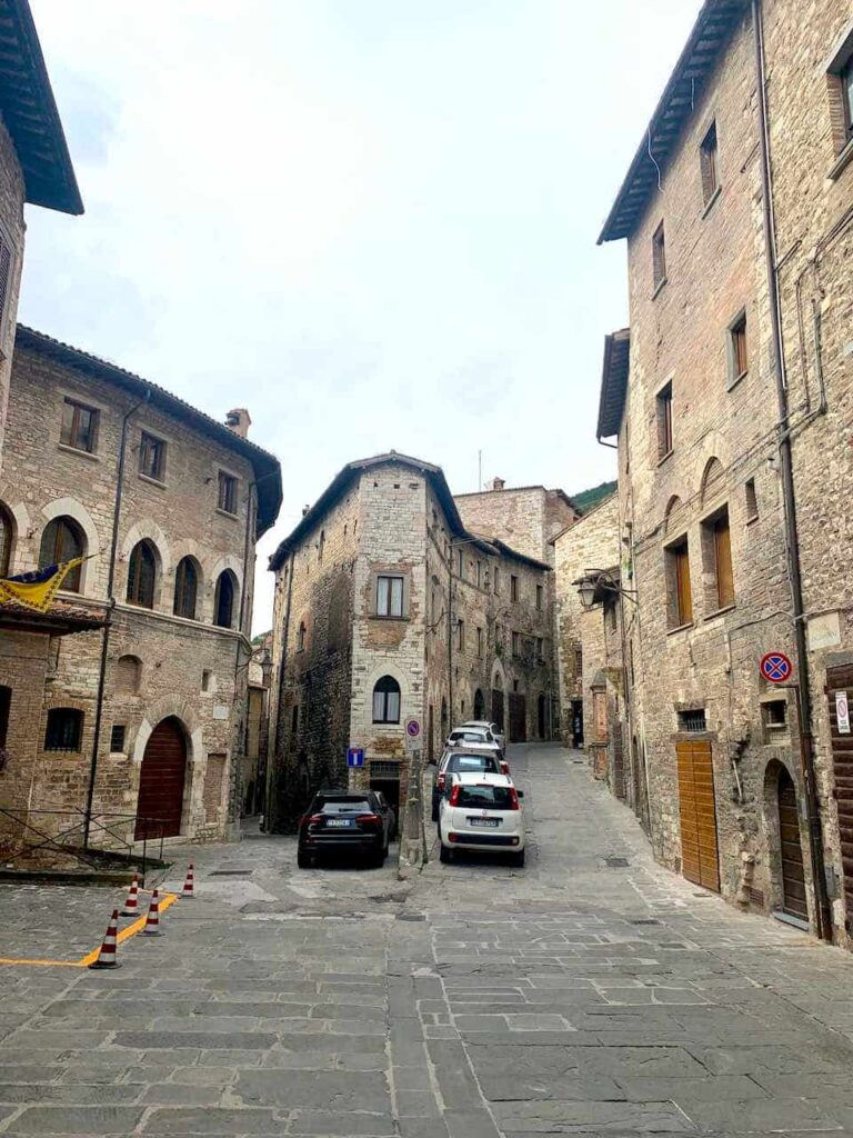Narrow medieval stone street in the historic town of Gubbio, Umbria, Italy, lined with old stone buildings