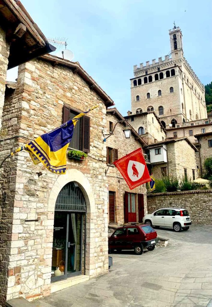 Medieval stone street in Gubbio, Umbria, Italy, with the tower of the Palazzo dei Consoli rising in the background