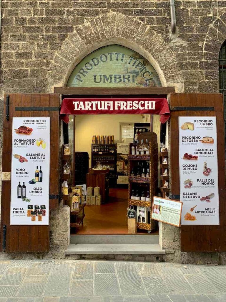 Specialty shop on a medieval stone street in Gubbio, Italy, selling Umbrian truffles, local wines and cured meats